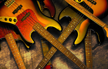 Red and yellow bass guitars stacked in disarray - obrazy, fototapety, plakaty
