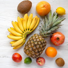 Set of fresh tropical fruits on a white wooden surface, overhead view. Closeup.