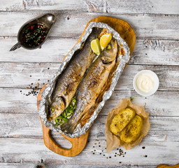 Fresh baked fish sea bass (Dicentrarchus labrax) on a light wooden background