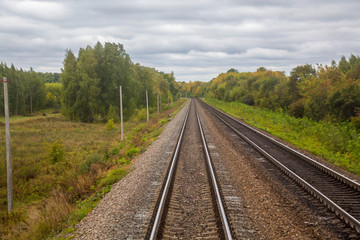 Fototapeta na wymiar Railway. View from the window of the last train car or from the cab. Russian autumn landscape. Railway rails and sleepers.