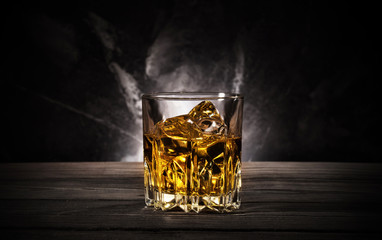 Glass of whiskey with ice on black background