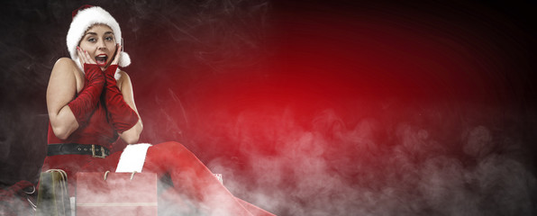 Slim young Santa Claus woman and dark red background with smoke. Free space for your text 