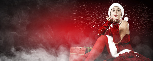 Slim young Santa Claus woman and dark red background with smoke. Free space for your text 
