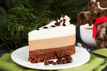 Three chocolate mousse cake slice on a small plate. A trio of milk, dark and white chocolate combined in a delectable mousse. Christmas background.