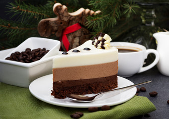 Three chocolate mousse cake slice on a small plate. A trio of milk, dark and white chocolate combined in a delectable mousse. Christmas background.
