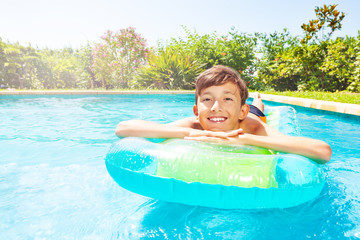 Teen boy relaxing on air mattress in swimming pool