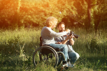 Disabled woman look on the taken photos on camera.