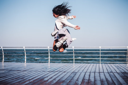 Mid adult woman jumping mid air on sea pier, Odessa, Odeska Oblast, Ukraine