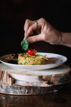 Young woman putting basil garnish on food, close up of hand