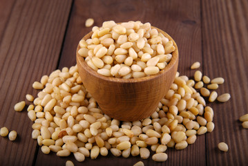 Kernels of pine nuts in a bowl on a dark wooden background.