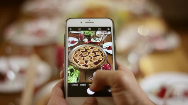 Smartphone taking a vertical photo of pie on Christmas served table