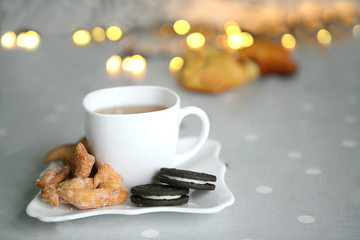 white cup of tea and pastries.  Festive bokeh in the background