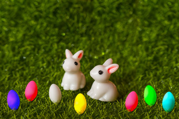 two figures of a rabbit and colorful eggs on the grass. happy Easter concept
