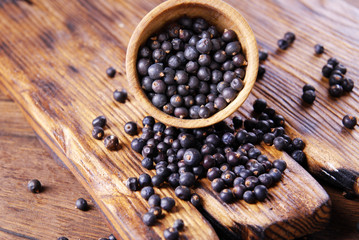Dry black currant in a bowl on a wooden background.