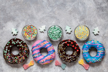 homemade doughnuts with colored frosting and different sprinkles on a gray background