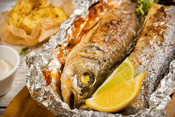 Fresh baked fish sea bass (Dicentrarchus labrax) on a light wooden background