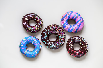 homemade doughnuts with colored frosting and different sprinkles on white background