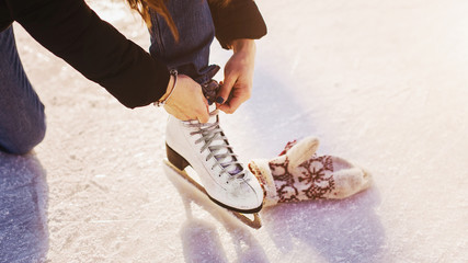 Girl in dress skates mittens tying shoelaces and prepare for skating - obrazy, fototapety, plakaty