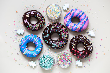 homemade doughnuts with colored frosting and different sprinkles on white background