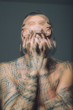 Multiple exposure of bare chested young man, covered in tattoos, screaming