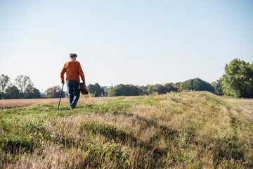 Naklejka na ściany i meble Senior man carrying traveling bag, walking in the fields