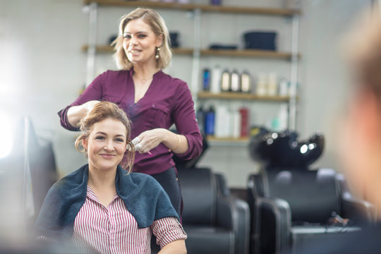 Hairdresser styling customer's hair in salon