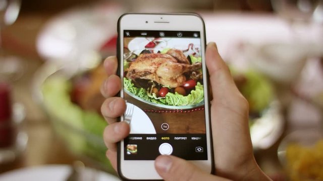 Smartphone taking a vertical photo of turkey on Christmas served table