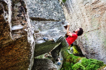 Boy bouldering outdoor on a stone