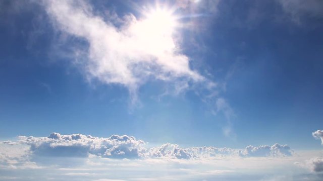 White flufly clouds passing blue sky with bright sun shining