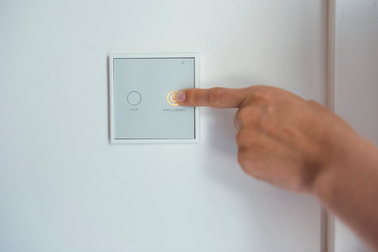Woman using smart home switch on wall