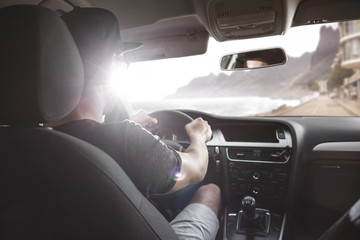 Mann im Auto fährt auf einer Straße am Meer