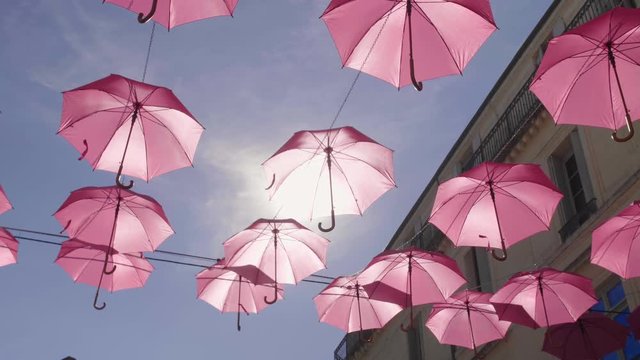 Pink umbrellas suspended in Montpellier streets preventive breast cancer campaign.  