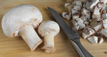 Sliced mushroom with knife lies on a kitchen wooden board. Side view. Health and vegetarian concept.