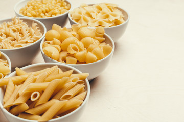 Different pasta types in bowls on the table.