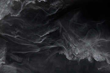 abstract swirls of grey paint on black background
