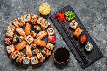 sushi rolls Asian food on a round slate black Board with wasabi and ginger, soy sauce