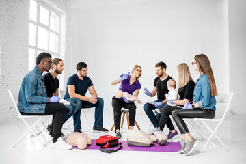 Group of people during the first aid training with instructor showing on manikin how to do artificial respiration for the baby