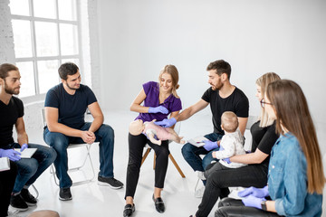 Group of people during the first aid training with instructor showing on manikin how to do...