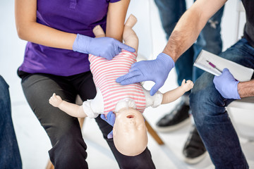 Showing on baby model how to do artificial respiration for the baby during the first aid training