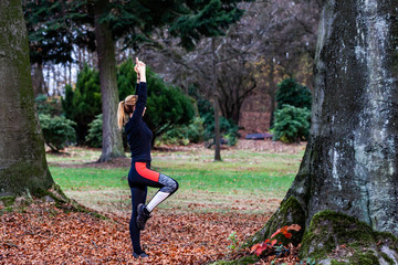 Concept of young lady doing yoga exercises outdoors in the forest