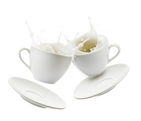 Cups full of milk bump and splashing, isolated on white background