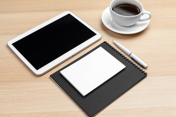 Digital tablet with notepad, supplies and coffee cup on desktop.