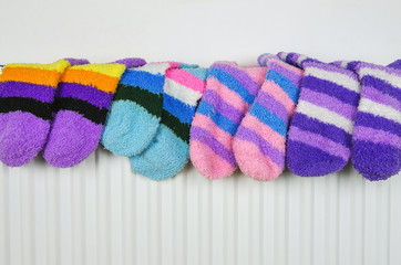 Multi colored warm terry socks drying on heater. 