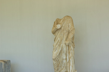 destroyed ancient antique marble sculpture of unknown philosopher without head on white empty wall...
