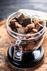 Pieces of dark bitter chocolate with cocoa and nuts almonds on wooden background. Concept of confectionery ingredients