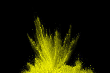 Freeze motion of yellow dust explosion isolated on black background.