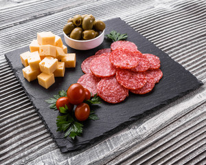 delicious sliced salami on a stone plate wooden background