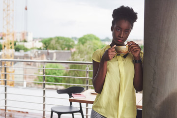 Beautiful young African American business woman drinking coffee at a cafe. Beautiful cozy place