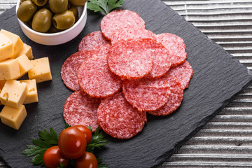 delicious sliced salami on a stone plate wooden background - obrazy, fototapety, plakaty