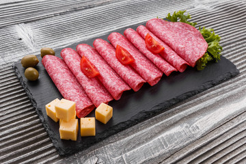 delicious sliced salami on a stone plate wooden background
